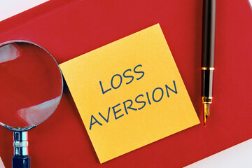 Business concept. LOSS AVERSION text on a yellow sticker on a red business notebook in a...