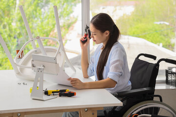 Young Asian woman in wheelchair with drill and manual assembling chair at home