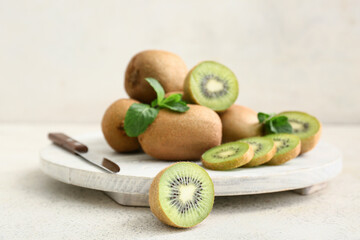 Board with fresh kiwi and mint on white background