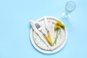 Beautiful table setting with dandelion flowers on blue background