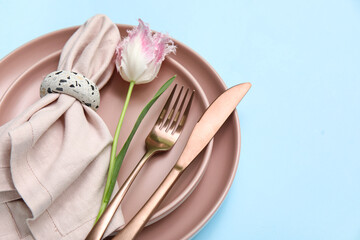 Stylish table setting with beautiful tulip on blue background