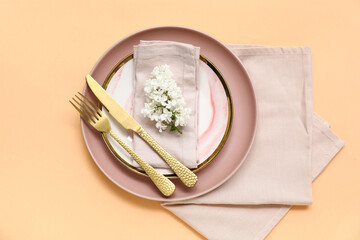 Beautiful table setting with lilac flowers on orange background