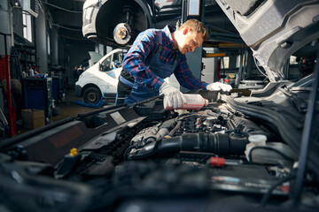 Young male adds coolant to cooling system