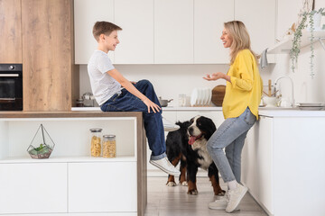 Little boy and his mother with Bernese mountain dog in kitchen