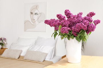 Vase with beautiful lilac flowers on chest of drawers in bedroom