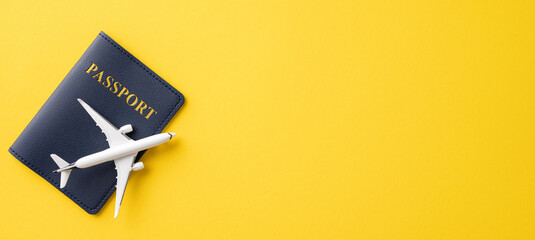 Passport and small airplane model against a yellow background, representing travel and adventure