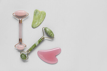Jade rollers and gua sha on grey background