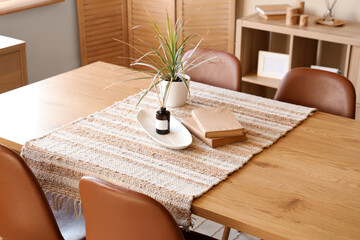Dining table with reed diffuser, books and houseplant at home