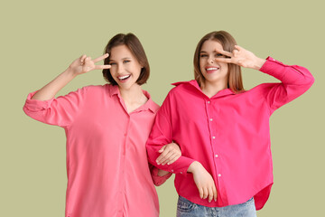 Female friends showing victory gesture on green background