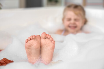 Cute little girl taking bath in bathroom, closeup