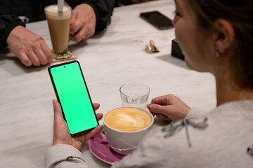 Mujer sosteniendo un teléfono móvil con la pantalla verde chroma key. Recurso gráfico para...