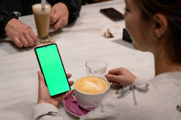 Mujer sosteniendo un teléfono móvil con la pantalla verde chroma key. Recurso gráfico para publicidades y anuncios