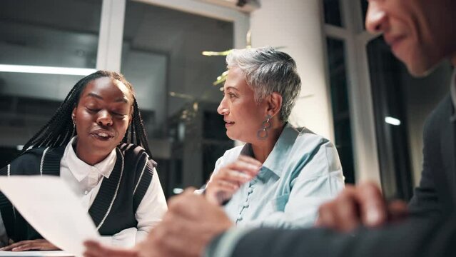 Business people, document and meeting at night for teamwork, support or editing advice at publishing company. Senior writer, editor and group with paperwork or talking of article or project feedback
