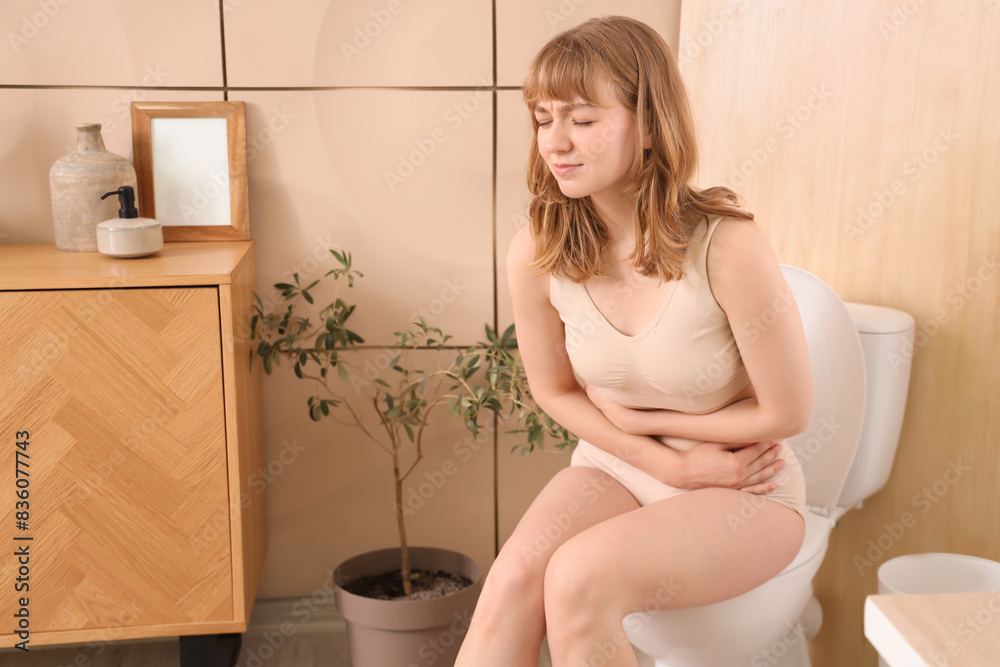 Canvas Prints young woman suffering from menstrual cramps on toilet bowl in restroom