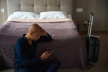 Obraz premium African american businessman watching and using smartphone on floor by bed