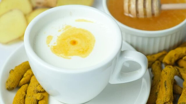 Making milk with turmeric. Turmeric powder pouring into a cup of warm milk, slow motion