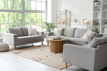Interior of light living room with grey sofas and magazines on coffee table