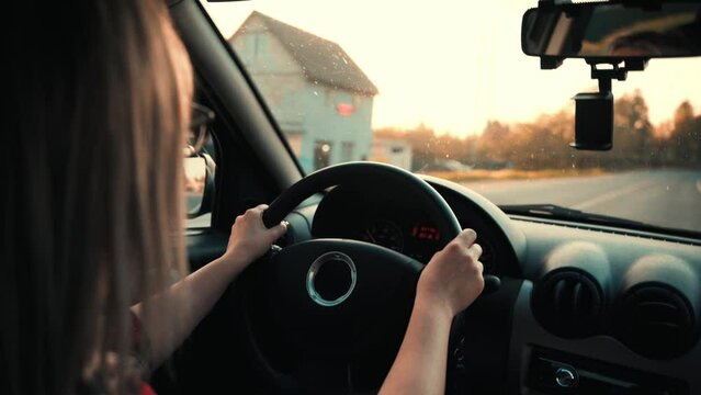 A young beautiful woman is driving a car. the sun's rays. cinematic view