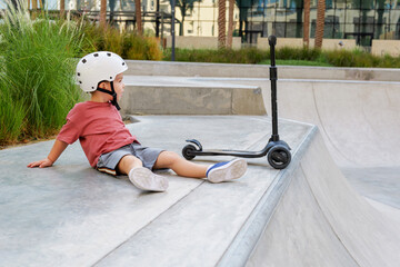 little boy wearing a helmet and with his scooter in a skate park © Ekaterina Elagina