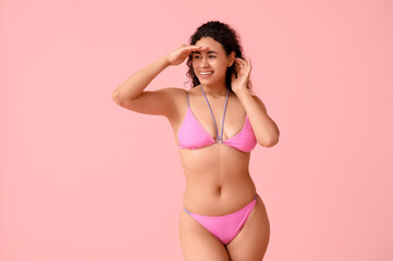 Beautiful young African-American woman in stylish swimsuit on pink background