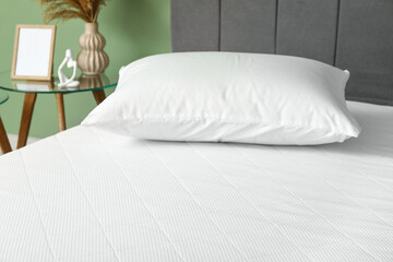 Obraz premium New orthopedic mattress on stylish bed near green wall in room, closeup