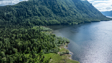 beautiful landscape with mountains and Lake Teletskoye against a background of blue sky from a drone in May