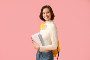Beautiful female student with backpack and books on pink background