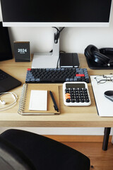 Desktop with notepads, laptop, monitor, keyboard, mouse, headphones on a light background