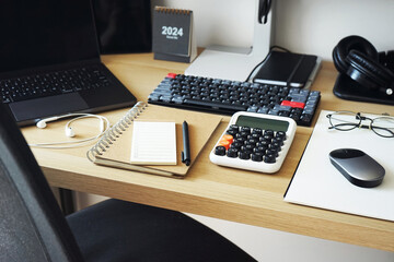 Desktop with notepads, laptop, monitor, keyboard, mouse, headphones on a light background