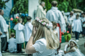 Pierwsza komunia, dziewczynka z wiankiem na głowie zasłania dłońmi oczy © Mariusz