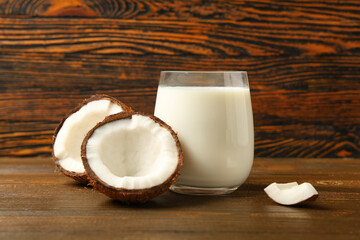 Glass of natural coconut milk on brown wooden background