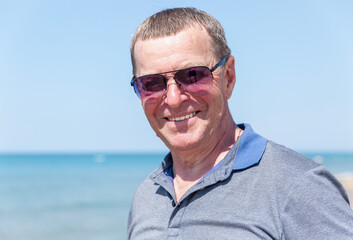 An elderly man in sunglasses at the sea. Tourism and travel. Close-up.