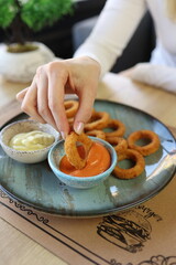 Hands holding a plate full of squid and fried onions.