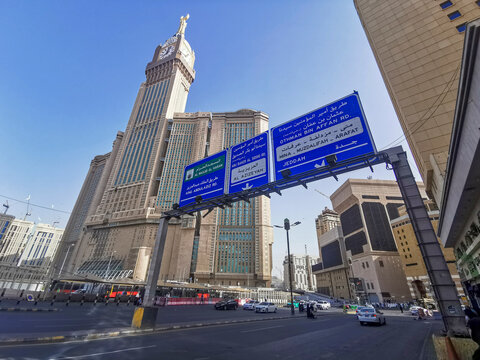 MECCA, KINGDOM OF SAUDI ARABIA (KSA) - 8 JUNE, 2023 :Makkah Clock Tower or Abraj Al Bait tower (left) and major cities road signs in Makkah, Saudi Arabia..