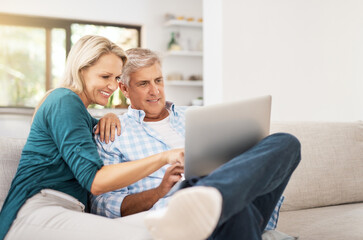 Couple, couch and laptop with smile in home, streaming and relax in living room for movies. Internet, computer and point for website for video with married people, calm and lounge with technology pc