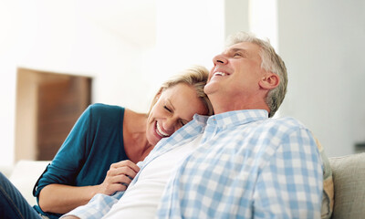 Mature, man and woman with laugh for relax on sofa, discussion with comedy in home. Happy couple,...