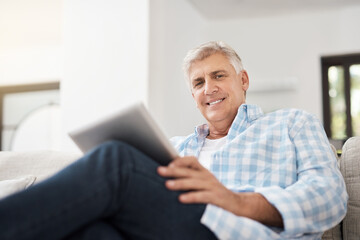 Portrait, tablet and mature man on sofa for communication, networking or reading news article in...