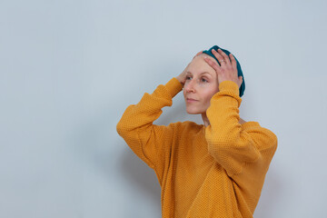 Pensive woman ill of cancer touching her head in turquoise hat