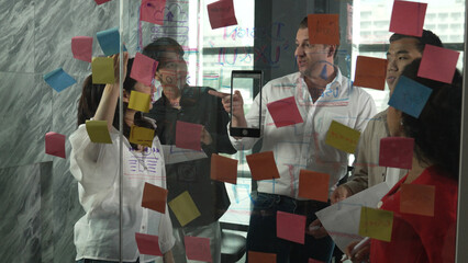 Portrait of professional business team brainstorming marketing idea by using sticky notes to share...