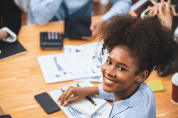 Portrait of happy young african businesswoman with group of office worker on meeting with screen display business dashboard in background. Confident office lady at team meeting. Concord