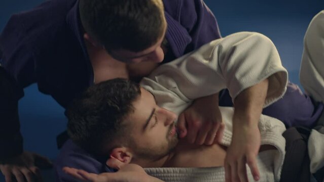 Handheld shot of judoka strangling his opponent on the judo mat. Slow-motion shot