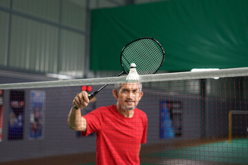 senior badminton player use racquet hit shuttlecock on the net while practice before tournament...