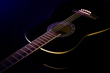black guitar concept. black guitar in the dark lit by blue light