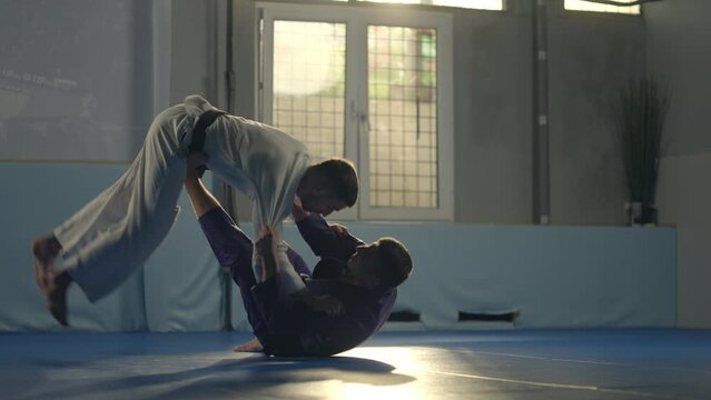 Athletes judoka fight on the floor in a fight club. Fighter makes a capture of the enemy and inflicts a painful reception