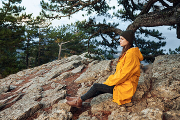 A woman in a vibrant yellow raincoat enjoying serene mountain vistas with lush trees in the...