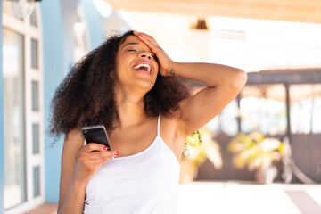 Young African American woman using mobile phone at outdoors has realized something and intending...
