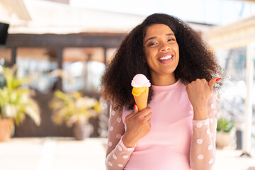 Young African American woman with a cornet ice cream at outdoors pointing to the side to present a...