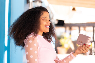 Young African American woman holding a wallet at outdoors with happy expression