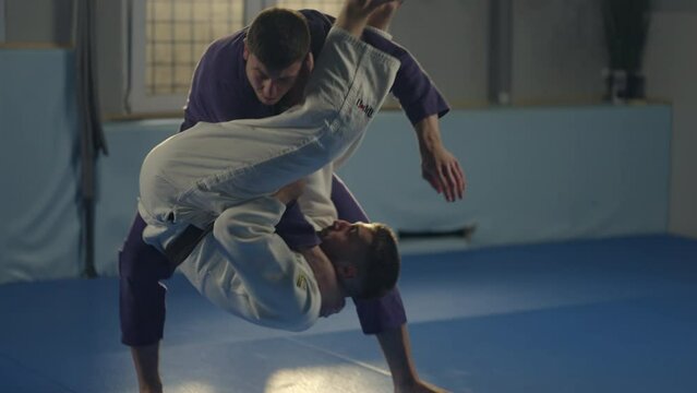 Slow-motion shot of two young karate boys practicing together on the judo mat in the gym