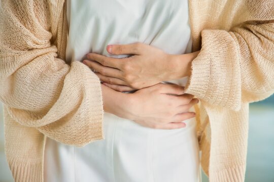 Hungry Asian woman with stomach ache, concept image of menstrual period cramp, abdominal pain, food poisoning, gastritis